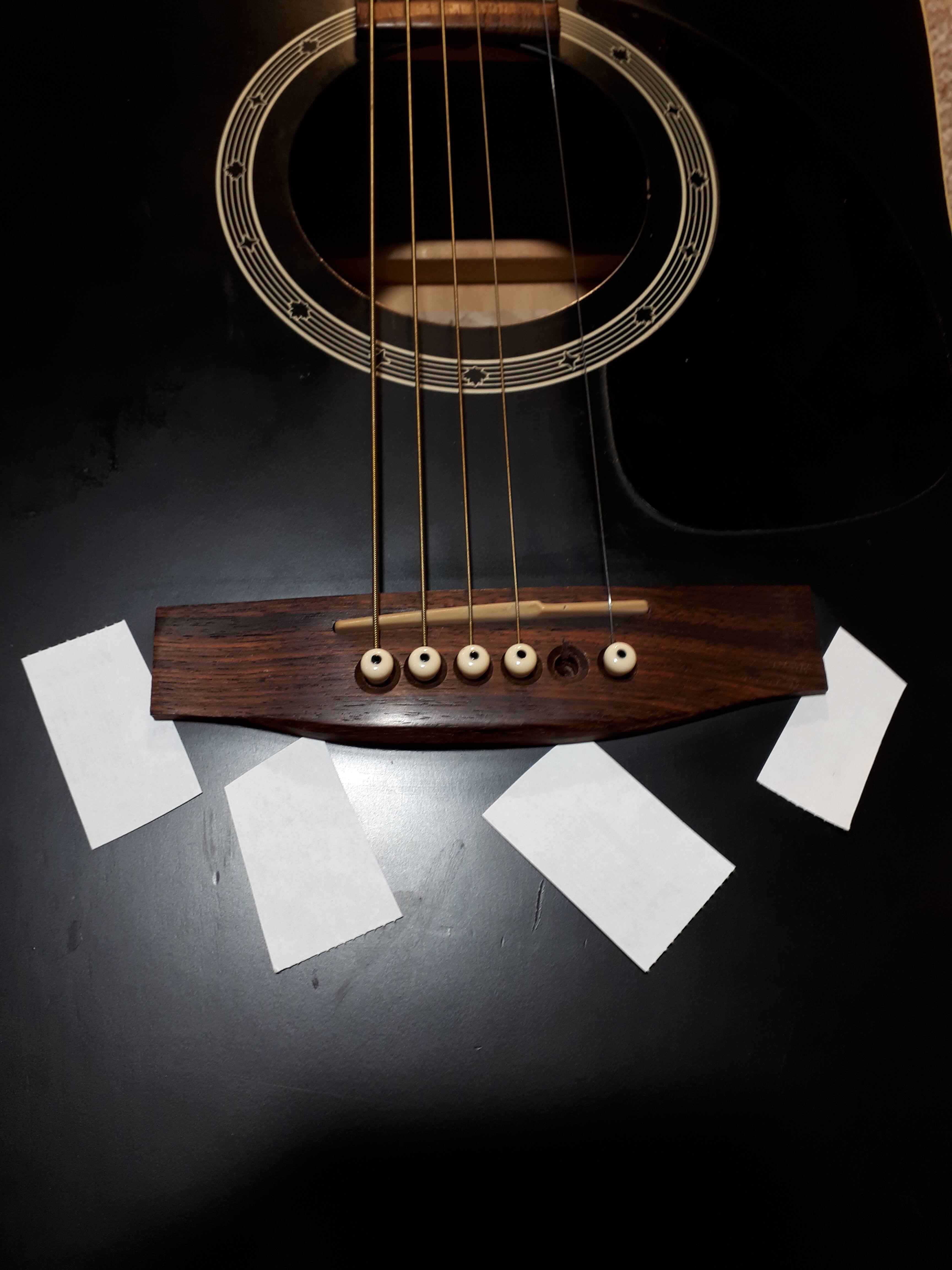 Bridge with paper under it demonstrating that it needs to be reset - Bridge Resets - Guelph Guitar Repair